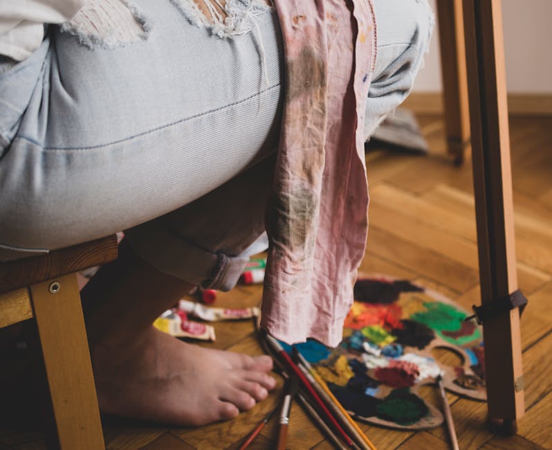 Close-up of an artist sitting inside, preparing to paint with brushes and apron.
