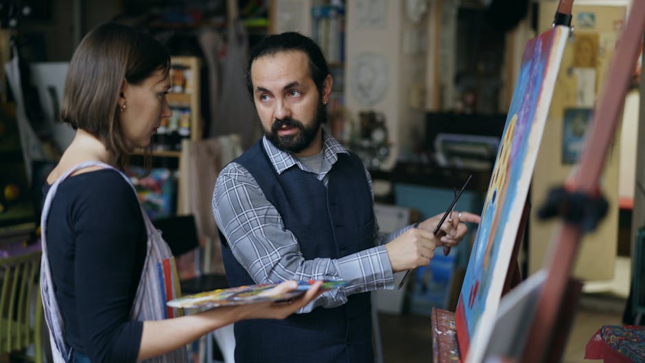 Art teacher guiding a student in painting techniques at an indoor studio.