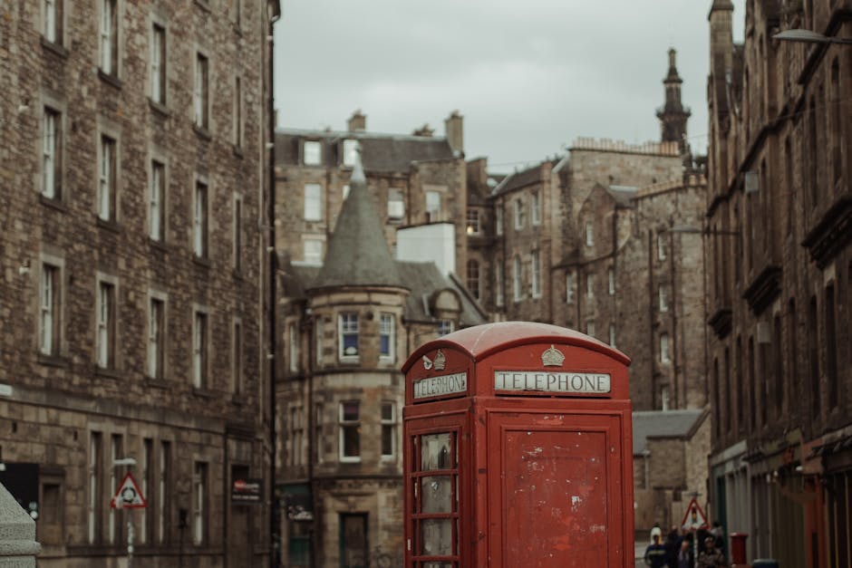 Classic red telephone booth in historic Edinburgh street, Scotland.