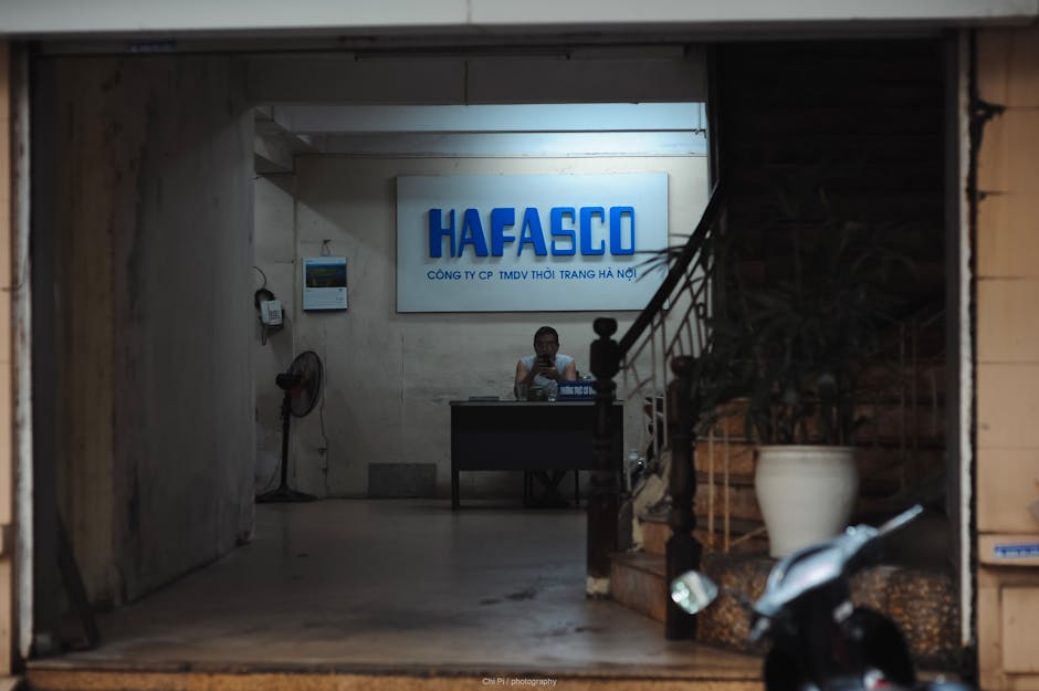 A man sitting at a desk under 'HAFASCO' signage in an office entrance.