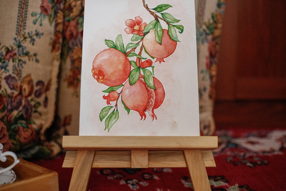 Watercolor painting of pomegranates set on a wooden easel indoors with a cozy background.